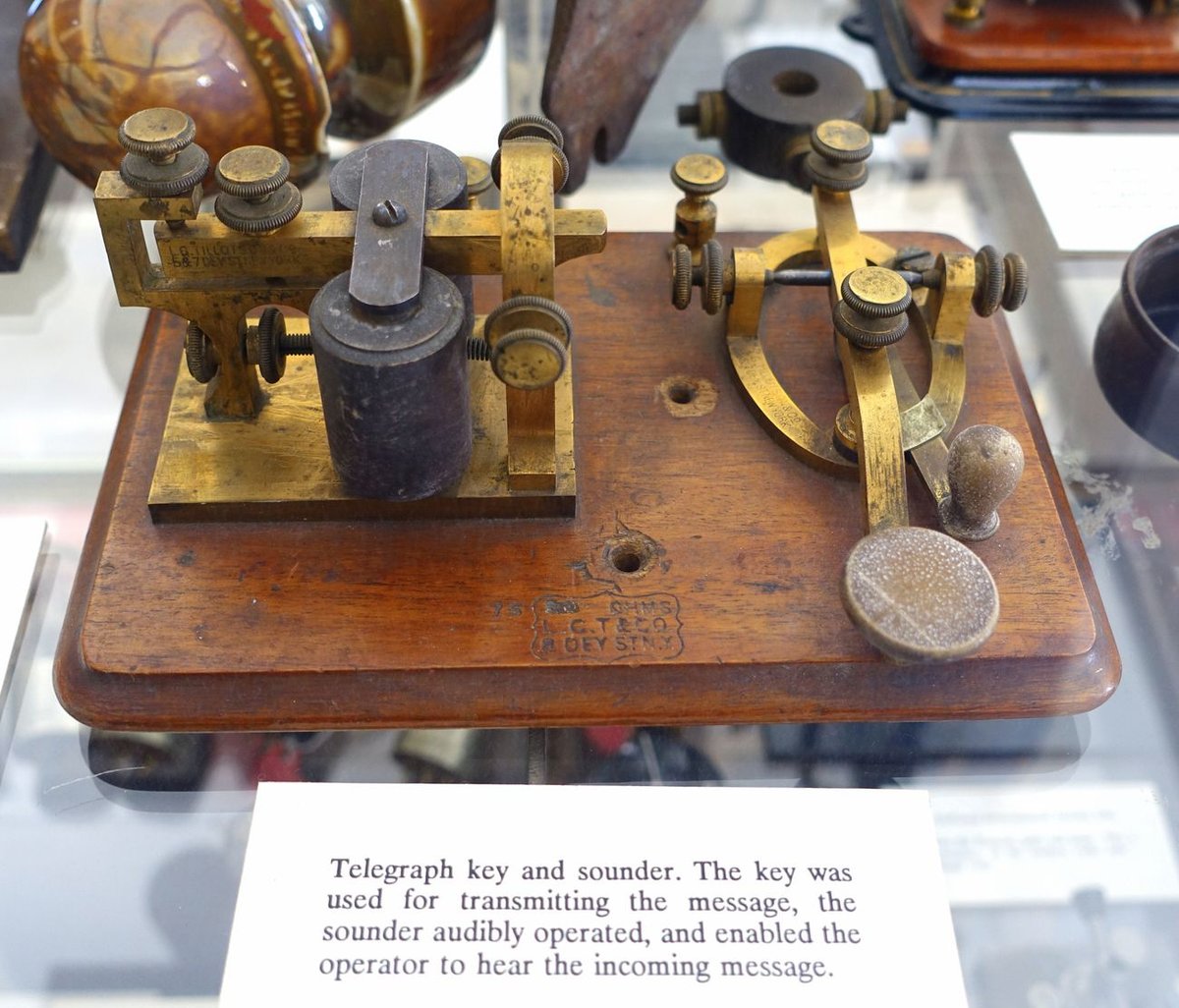 Figure 3 — A KOB (key-on-board) set by L. C. Tillotson & Co. of New York — a brass key and a brass sounder mounted together on one wooden board. Its museum label reads: "the key was used for transmitting the …