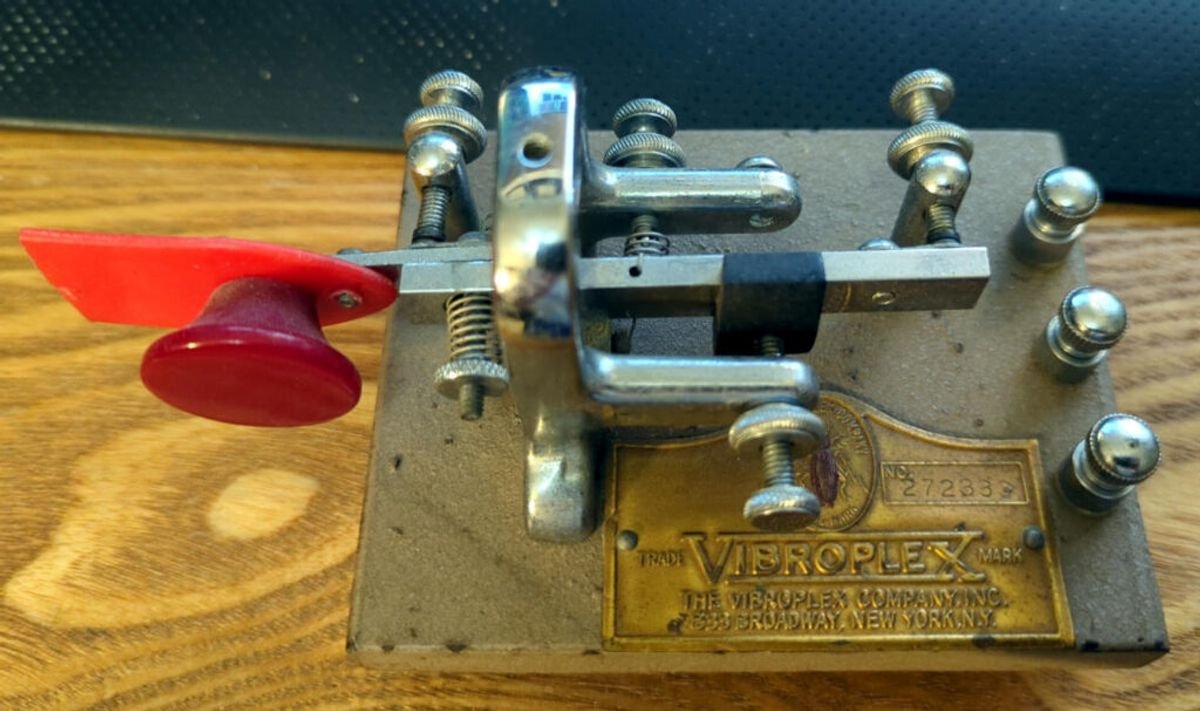 Figure 3 — A Vibroplex Vibrokeyer — a single-lever paddle (one red finger piece) built on a Vibroplex bug frame with the pendulum removed. One lever, total control of every element, and an unmistakable family…