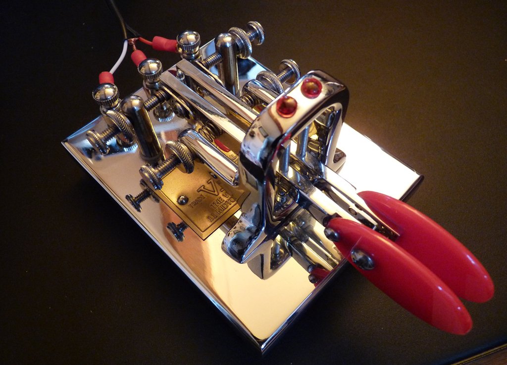 Figure 2 — A gleaming all-chrome deluxe Vibroplex with red finger pieces and a gold nameplate — the semi-automatic key as an object of desire. (This particular example is a custom twin-paddle deluxe, not the …