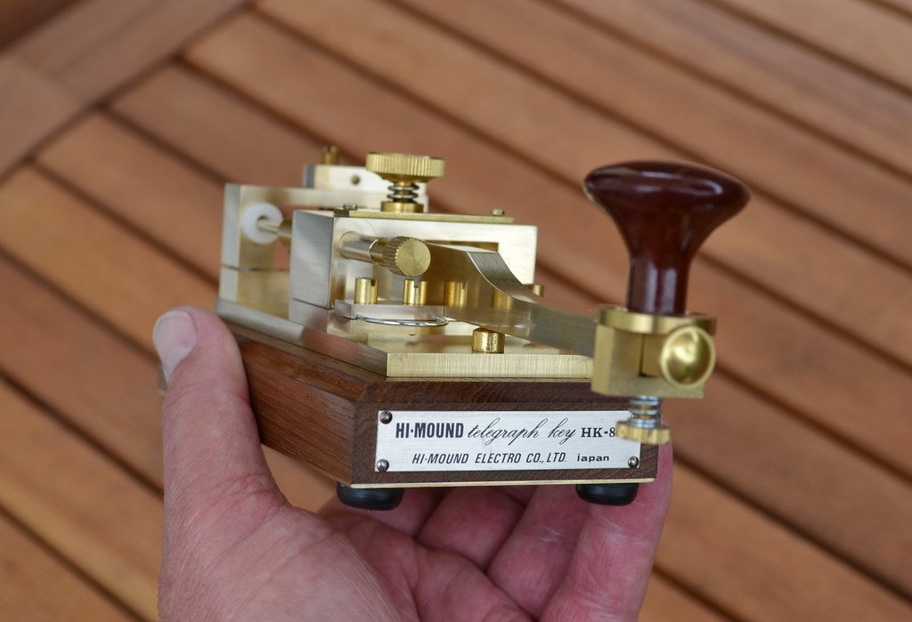 Figure 4 — A modern boutique brass key — a Hi-Mound HK-series solid-brass hand key (Hi-Mound Electro Co., the same firm behind the UFO autokeyer). The straight key as an object to buy once and keep for life. …