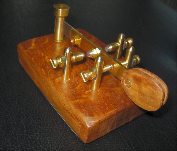 Figure 4 — A sideswiper ("cootie") — a single brass lever on a wooden base, worked side to side with a contact post on each side, to spare the wrist. Fully manual: it makes no automatic dits, unlike a bug. (H…